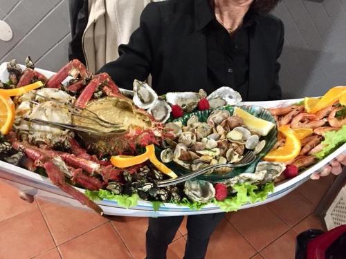 a woman holding a large platter of seafood at Alojamento Sudoeste in Zambujeira do Mar