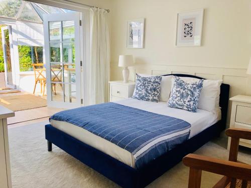 a bedroom with a bed with blue and white pillows at Secluded Spacious Garden Suite in Chichester