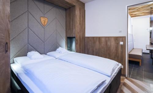 a bedroom with a large white bed with a wall at 24 by AvenidA - Mountain Hotel in Kaprun