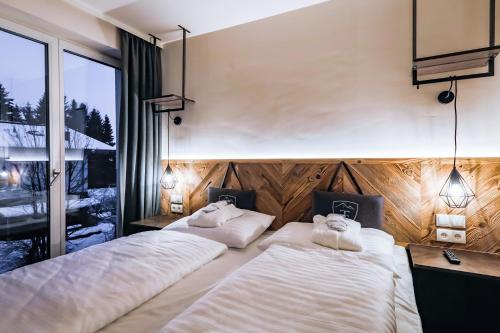 two beds in a room with a window at 24 by AvenidA - Mountain Hotel in Kaprun