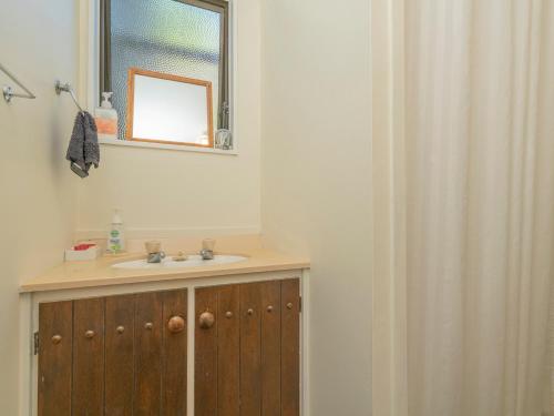 a bathroom with a sink and a mirror and a shower at Hahei Horizon - Hahei Holiday Home in Hahei