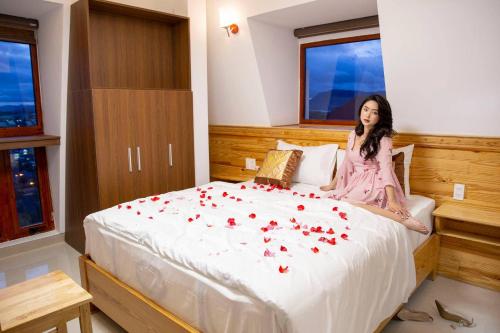a woman sitting on a bed with roses on it at Hoàng Yến Villa Dalat in Da Lat