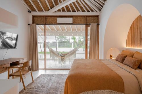 Schlafzimmer mit einem Bett und einer Glasschiebetür in der Unterkunft The White Joglo, feel the sea breeze from stylish 3BDR Villa W/Pool. in Canggu