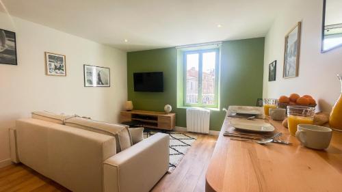 a living room with a table and a couch at Le Vert’ueux - Appartement tout équipé à Niort in Niort