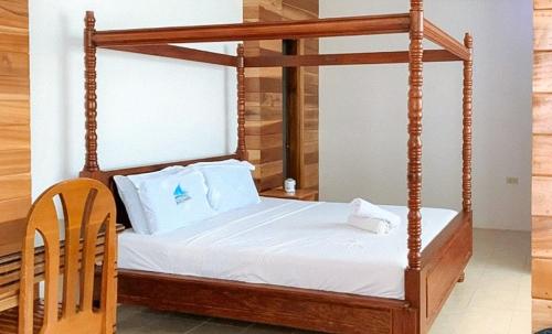 Cama de madera con dosel, sábanas y almohadas blancas en RedDoorz @ Almari Beach Resort Tawi-Tawi, 