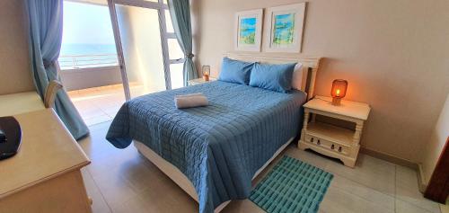 a bedroom with a bed with a blue blanket and a window at La Mer 8 - 6 Sleeper - Overlooking Margate Beach! in Margate