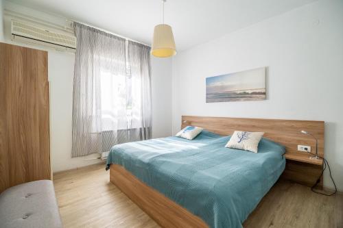 a bedroom with a bed with a blue blanket and a window at Apartment Černetič in Portorož