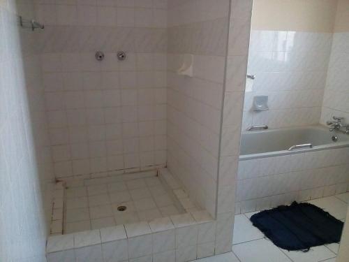 a bathroom with a shower with a tub and a tile floor at Neat guest suite with office corner - 2101 in Harare