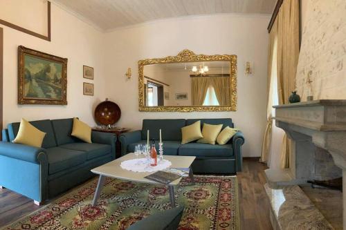 - un salon avec des canapés bleus et un miroir dans l'établissement Yiayias House Tzoumerka, à Plaka