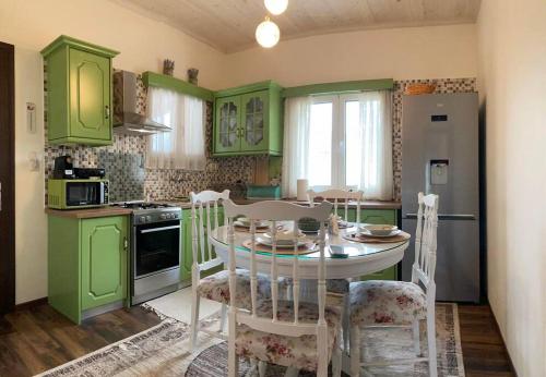 una cocina con armarios verdes y una mesa con sillas en Yiayias House Tzoumerka, en Plaka