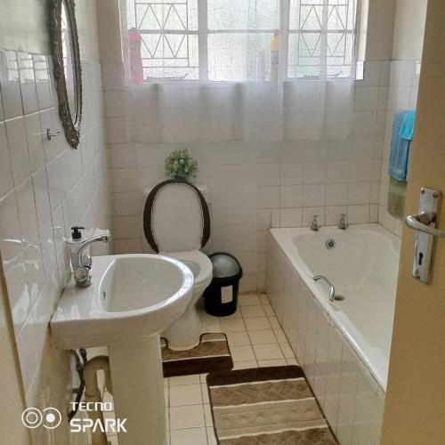 a bathroom with a sink and a toilet and a tub at Neat and cosy cottage with pool - 2103 in Harare