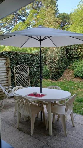 une table blanche avec des chaises et un parasol dans l'établissement STUDIO TERRASSE JARDIN VANNES, proximité port et centre historique, parking privé, à Vannes