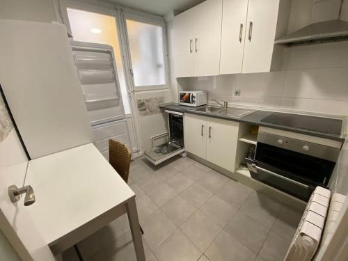 Apartamento acogedor en Logroño في لوغرونيو: مطبخ بدولاب بيضاء وفرن علوي موقد