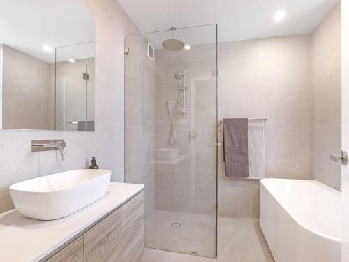 a white bathroom with a sink and a shower at Lavish 3-bedroom ocean apartment in Wollongong in Wollongong