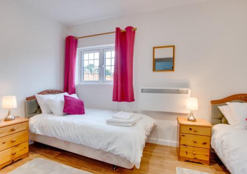 a bedroom with two beds and a window with red curtains at Little Haven in Easby