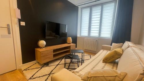 ein Wohnzimmer mit einem Sofa und einem Flachbild-TV in der Unterkunft Le Noir’issime - Appartement tout équipé à Niort in Niort