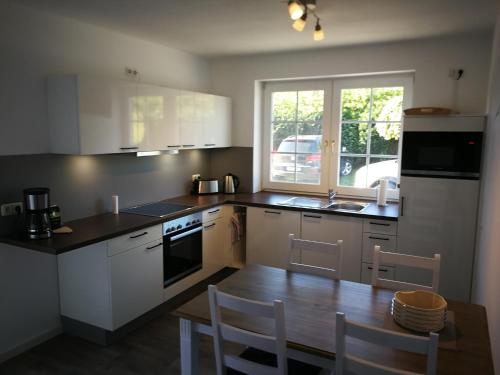 a kitchen with white cabinets and a table and chairs at Sundblick, ideal für Familien in Teschendorf