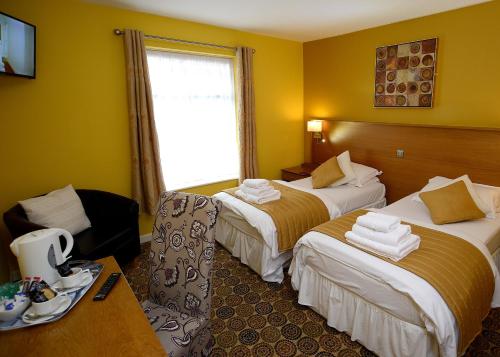 een hotelkamer met 2 bedden en een raam bij The Birley Arms Hotel Warton in Lytham St Annes