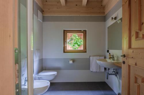 ein Bad mit 2 Waschbecken, einem WC und einem Fenster in der Unterkunft Hotel Chalet val di Rabbi in Rabbi