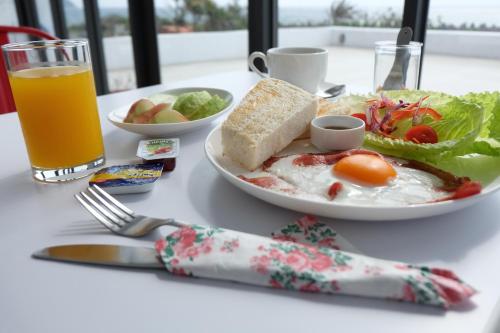 a table with a plate of breakfast food and a glass of orange juice at Sea Shore Hotel in Manzhou