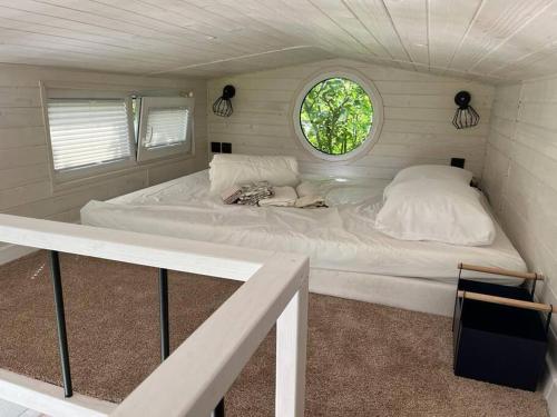 Cama blanca en habitación pequeña con ventana en La Tiny du paradis en Baigts-de-Béarn