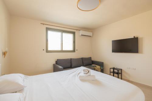 1 dormitorio con cama blanca y sofá en Shifra Suite en Beer Sheva