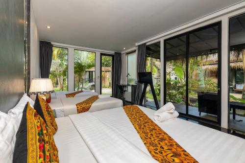 two beds in a room with large windows at Maison Gen Angkor in Siem Reap