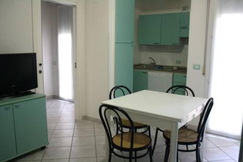 a kitchen with a white table and chairs and a tv at Residence Le Vele in Cattolica