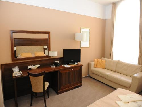a hotel room with a desk and a couch at Penzion Kiska Kežmarok in Kežmarok