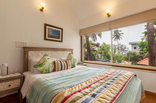 ein Schlafzimmer mit einem Bett und einem großen Fenster in der Unterkunft StayVista at Mawi Infinitty Beach View Villa - Arambol in Arambol