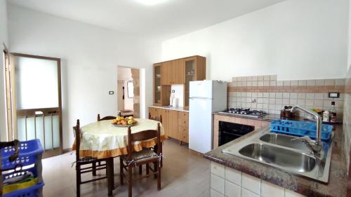 cocina con mesa y cocina con fregadero y nevera en Casa Marieli - A 50 Metri Dal Mare, Con Spazio Esterno en Gagliano del Capo