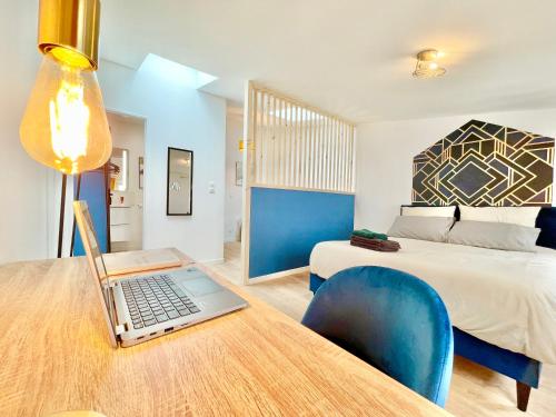 a bedroom with a bed and a laptop on a desk at Niort - Hyper-Centre - Appartements en Duplex ou Triplex - Wifi Fibre - NOUVEAU in Niort