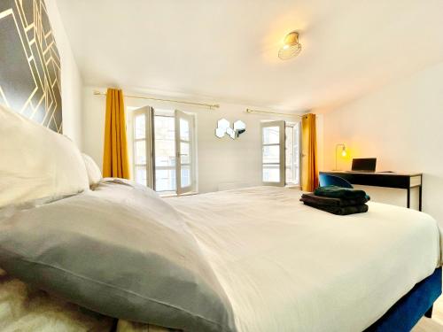 a bedroom with a large white bed with orange curtains at Niort - Hyper-Centre - Appartements en Duplex ou Triplex - Wifi Fibre - NOUVEAU in Niort