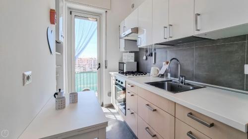 a kitchen with white cabinets and a sink and a window at Italianway - Voghera 11 B in Milan