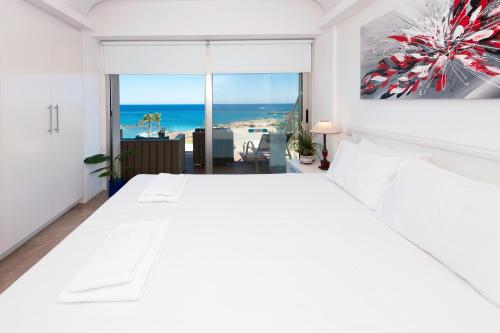 a white bedroom with a view of the ocean at Apartment Marina - Beachfront in Protaras