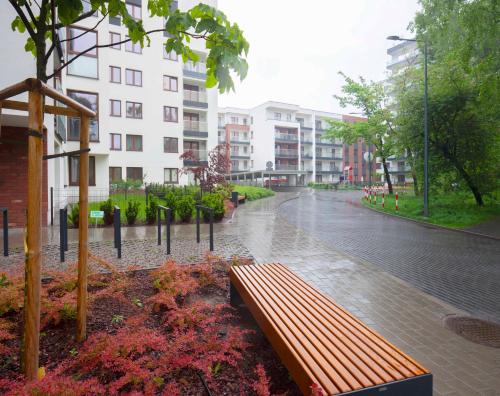 WAW Apartament Ursynow في وارسو: مقعد حديقة تحت المطر في شارع المدينة