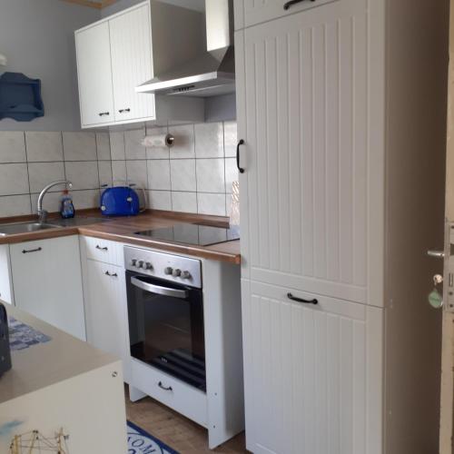 a kitchen with white cabinets and an oven at Bi uns im Norden in Brunsbüttel