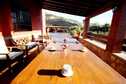 a wooden table with cups on top of a patio at TODIMER FINCA ALPUJAREÑA in Vélez de Benaudalla