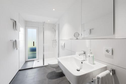 a white bathroom with a sink and a toilet at Ferienwohnung im Hubertushof in Feldberg