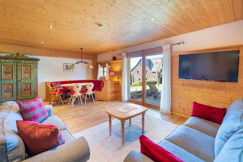 a living room with a couch and a tv and a table at Ferienwohnung im Hubertushof in Feldberg