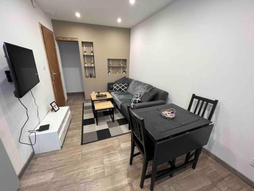 a living room with a black couch and a table at Beau T3 à Arcueil à 3 min RER B « Laplace » in Arcueil
