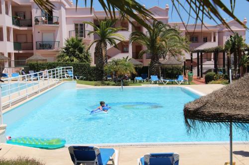 a woman swimming in a swimming pool at a resort at Luz Casas - St James 116, 2Bed/2Bath, Air Con, Shared Pool, Sea View in Luz