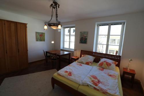 um quarto com uma cama, uma mesa e janelas em Altbautraum am Gärtnerplatz em Munique