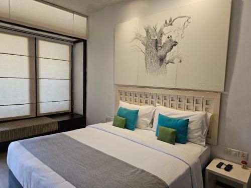 a bedroom with a large bed with blue and white pillows at Blue Breeze - Jetwing Select in Negombo