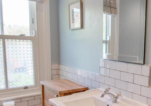 a bathroom with a sink and a mirror and a window at Honey Cottage in Richmond