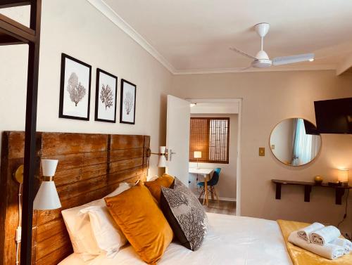 een slaapkamer met een bed met een houten hoofdeinde en een spiegel bij Dolphin Circle Bed and Breakfast in Plettenbergbaai