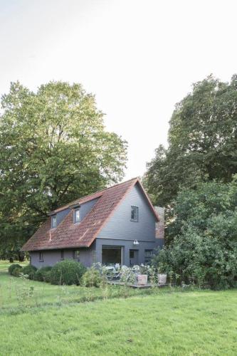 a gray house with a red roof in a field at Apartment im Kranich Hotel in Hessenburg