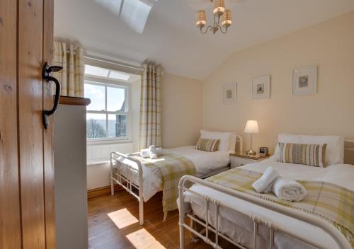 a bedroom with two beds and a window at Holly Tree Cottage in Aislaby