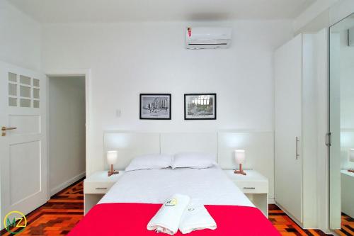 een slaapkamer met een wit bed en een rode deken bij Adorável 2 quartos em predio ART-DECOR in Rio de Janeiro