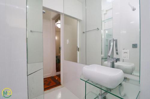een witte badkamer met een wastafel en een spiegel bij Adorável 2 quartos em predio ART-DECOR in Rio de Janeiro